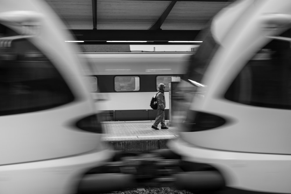 a black and white photo of a man standing next to a train