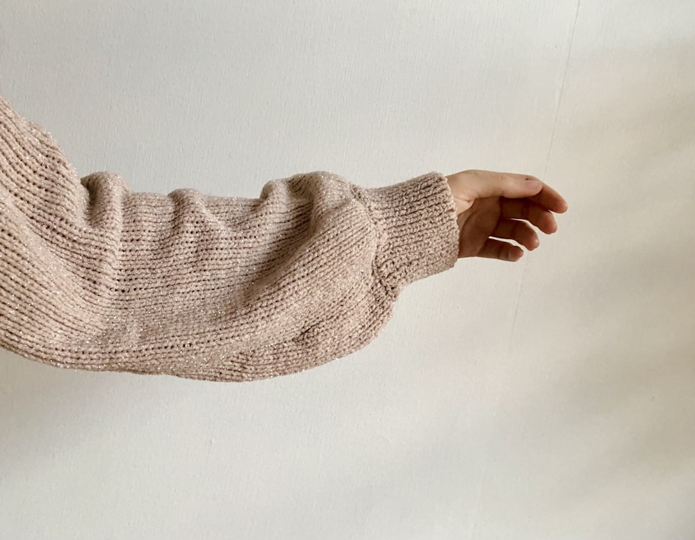 Der Arm einer Person mit einem Strickpullover