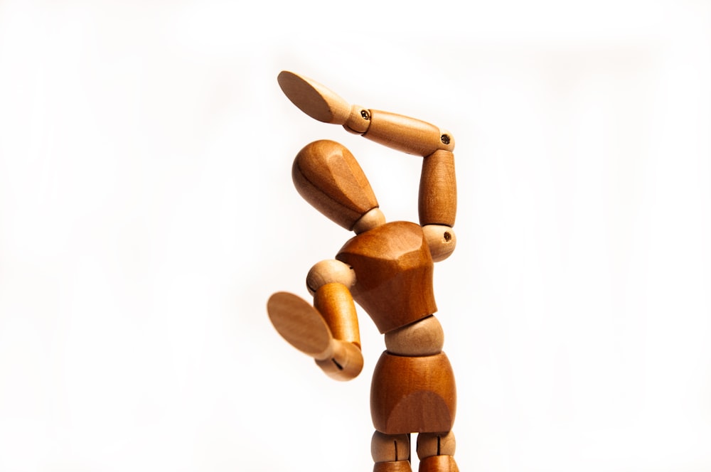 a wooden figurine holding a skateboard in the air