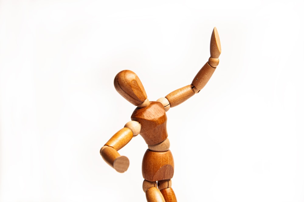 a wooden figurine of a person reaching up to catch a frisbee