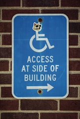 a blue sign on a brick wall that says access at side of building