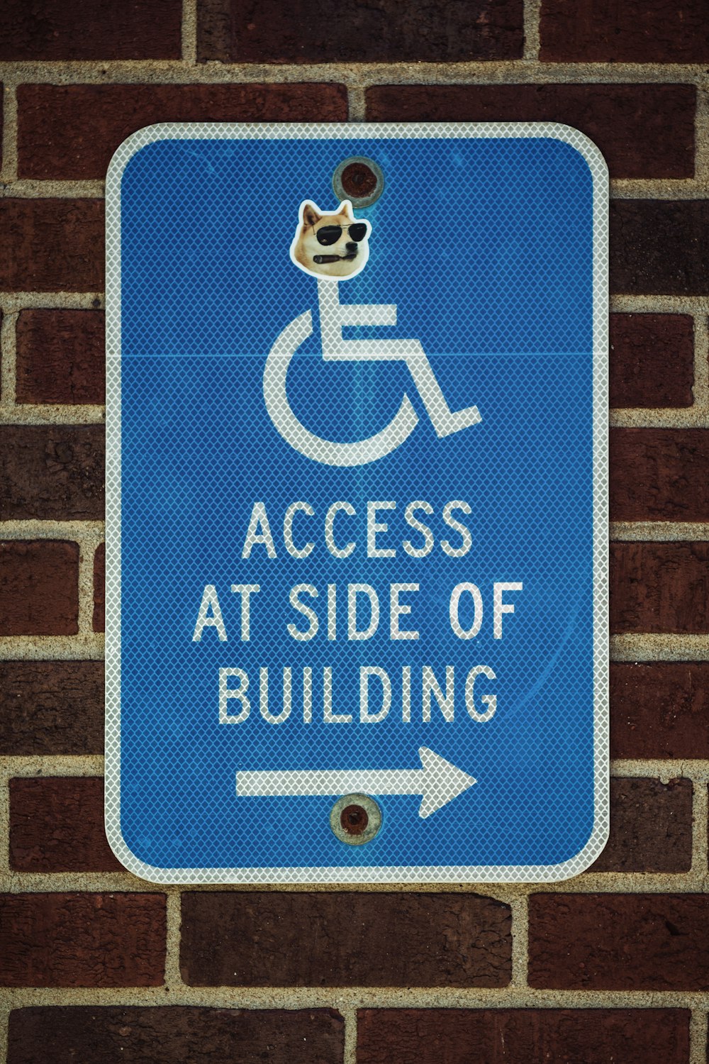 건물 옆에서 접근을 말하는 벽돌 벽에 파란색 표지판