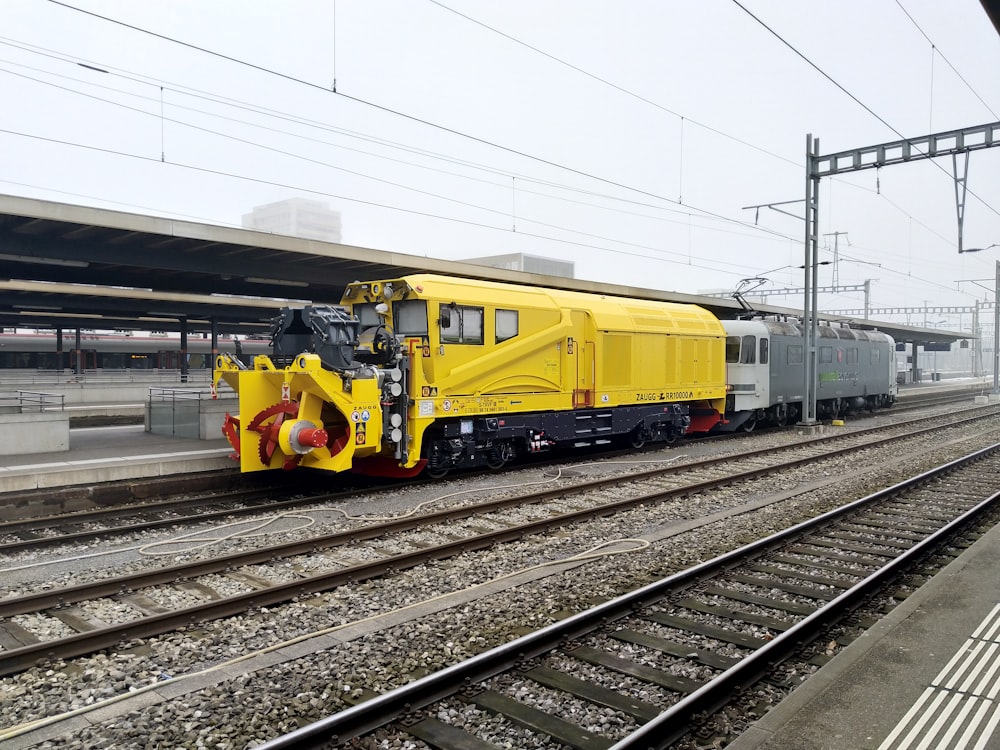 Ein gelber Zug, der neben einem Bahnhof die Bahngleise hinunterfährt