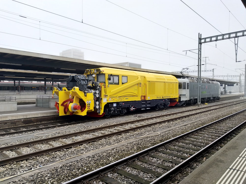 a yellow train traveling down train tracks next to a train station