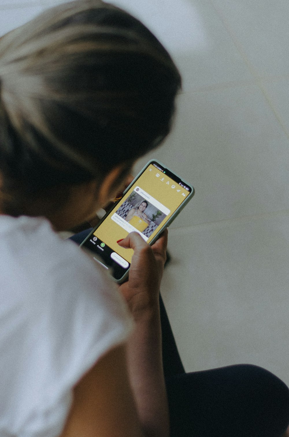 a woman sitting on the floor looking at her cell phone