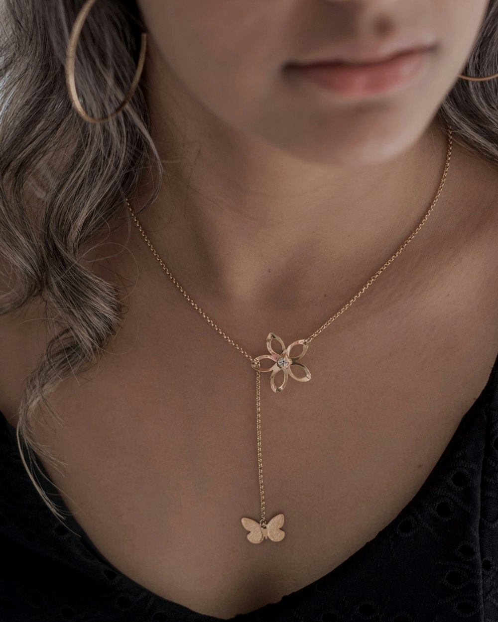 a woman wearing a necklace with a butterfly on it