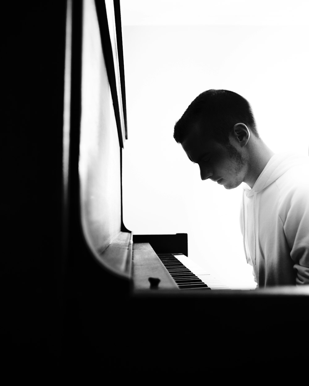 Un hombre de pie junto a un piano en una habitación oscura