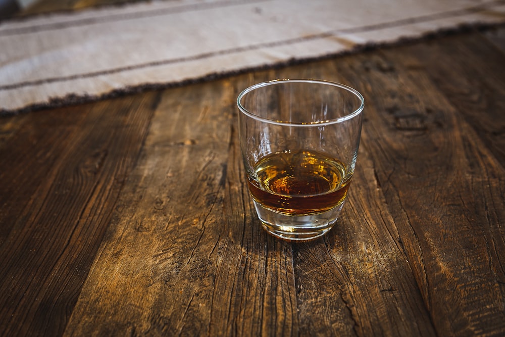 un bicchiere di whisky seduto su un tavolo di legno