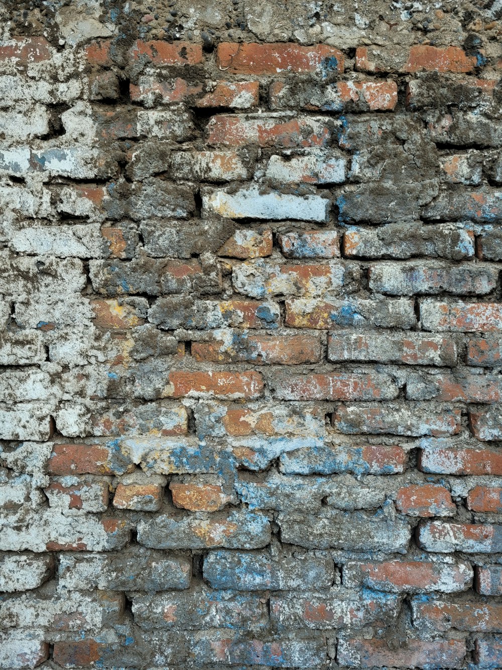 an old brick wall with some paint on it