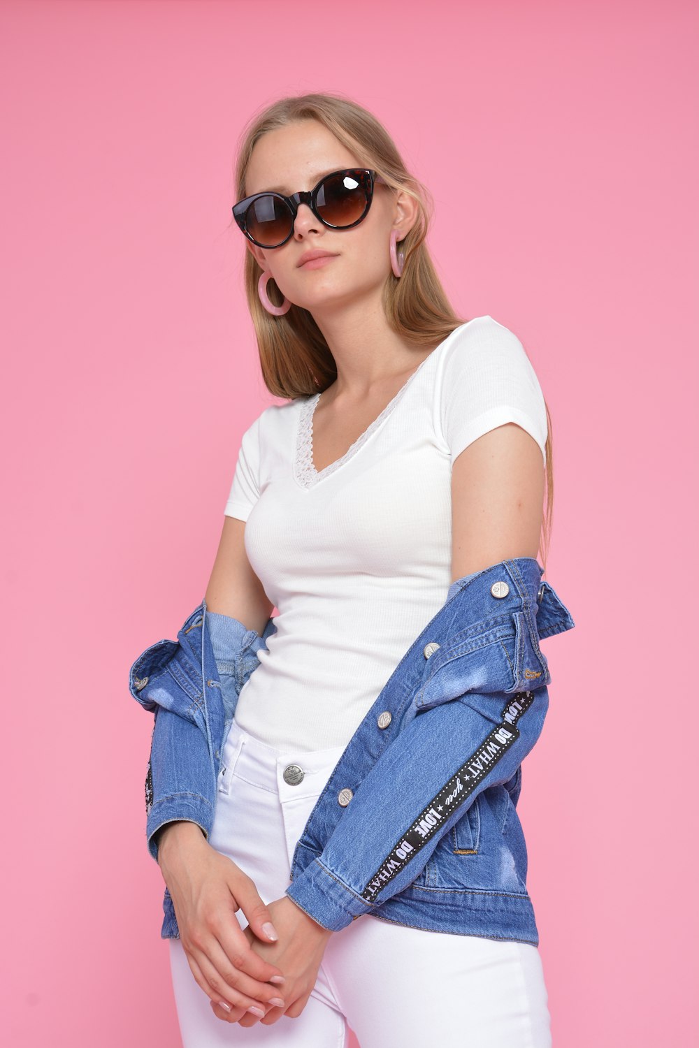 a woman wearing white jeans and a jean jacket