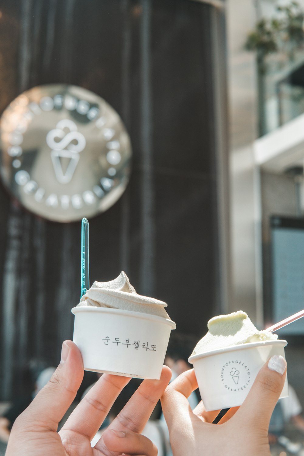 a person holding two cups of ice cream