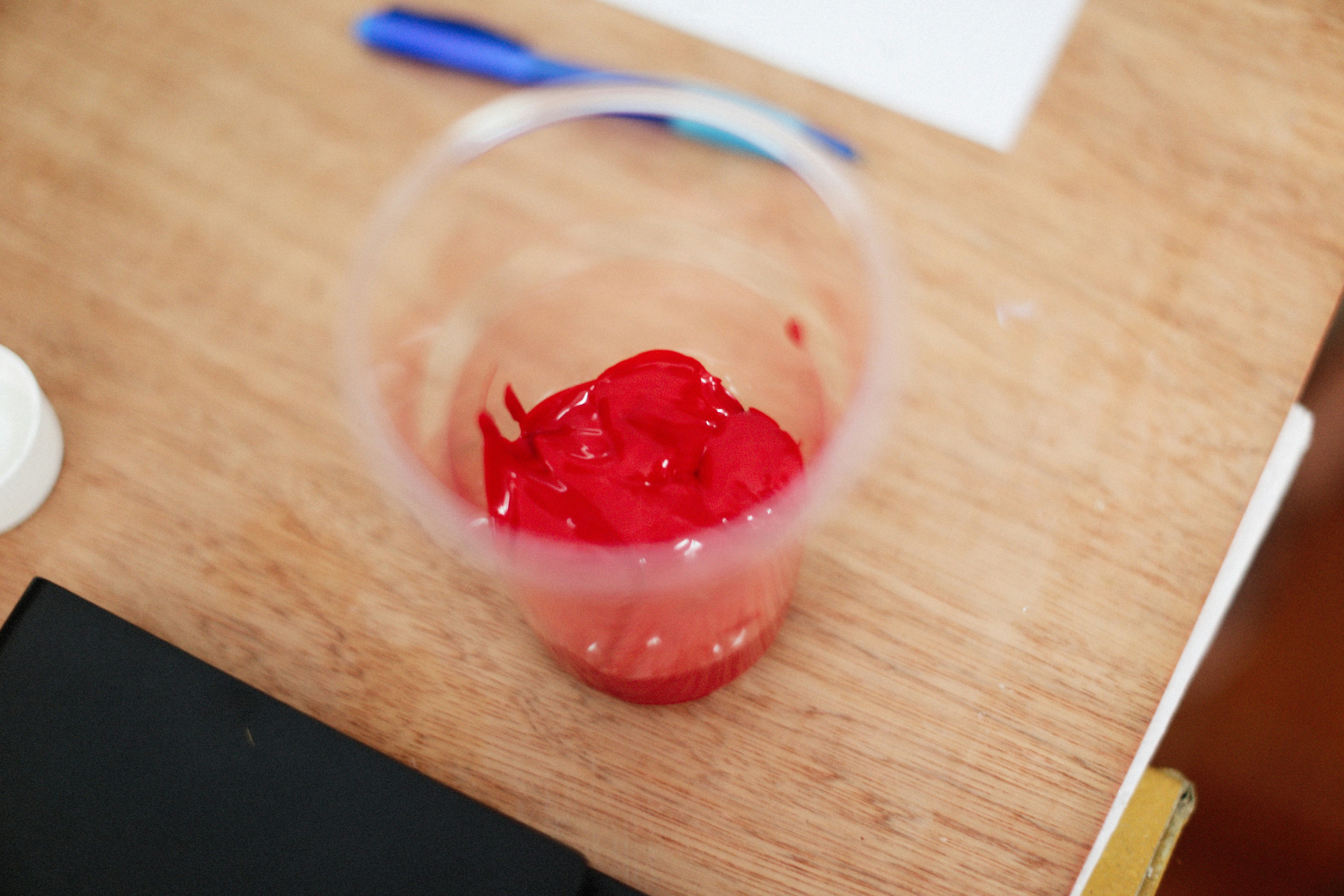 a glass filled with liquid sitting on top of a wooden table