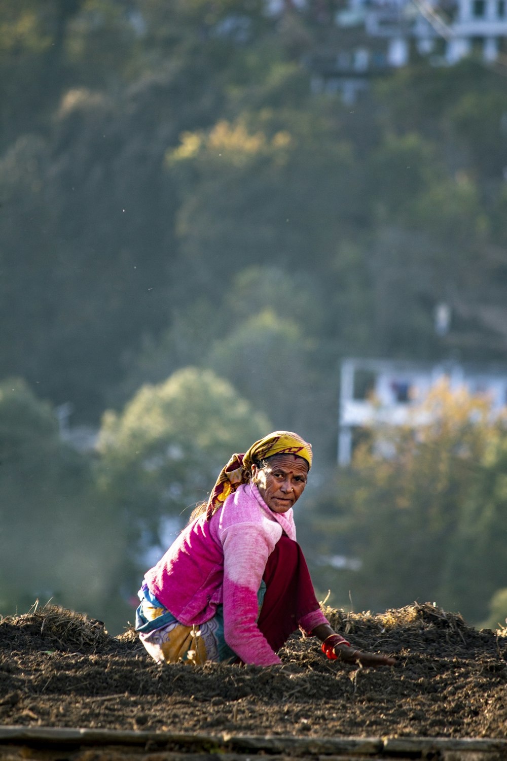 a woman kneeling down on top of a dirt field