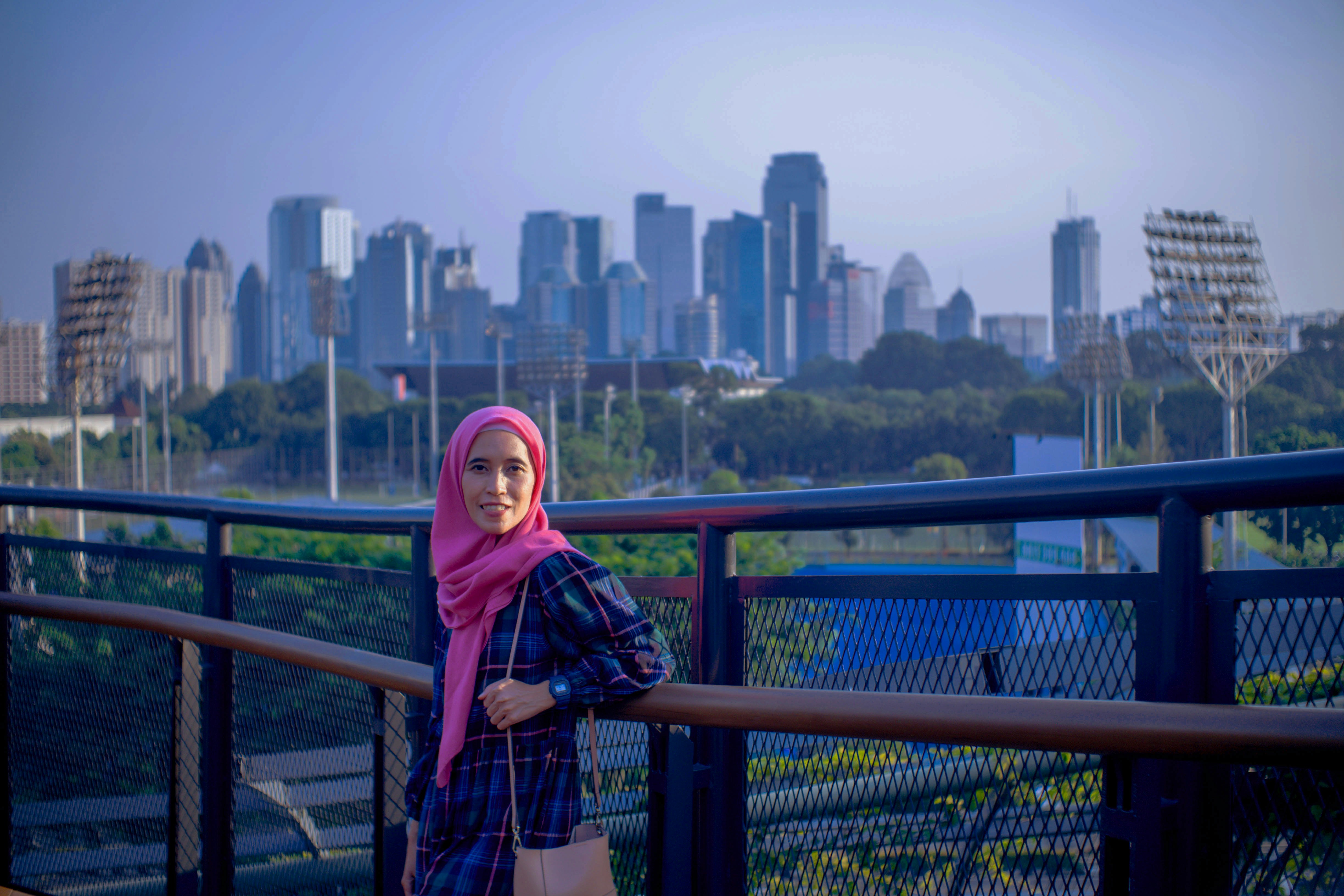 a woman standing on a bridge with a city in the background