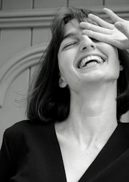 A candid portrait of a young woman laughing against a vibrant urban backdrop.