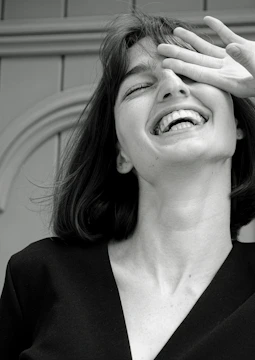 A candid portrait of a young woman laughing against a vibrant urban backdrop.