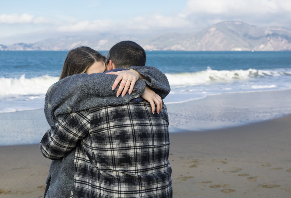 a man and a woman hugging on the beach