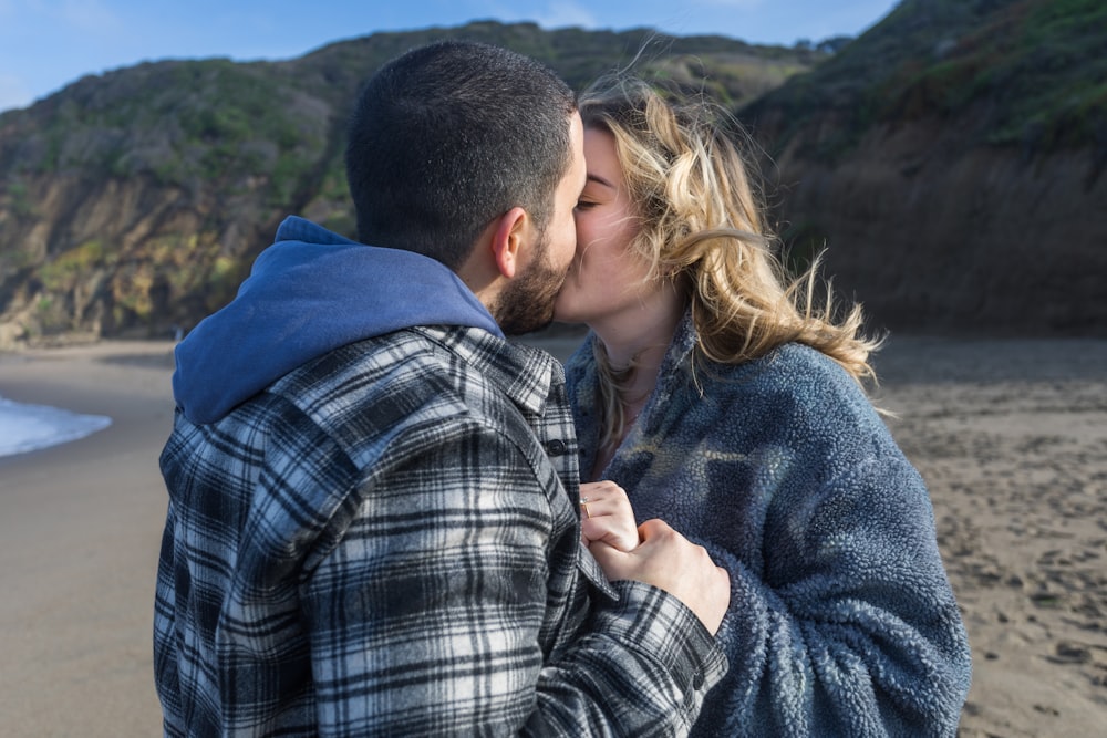 a man and a woman kissing on the beach