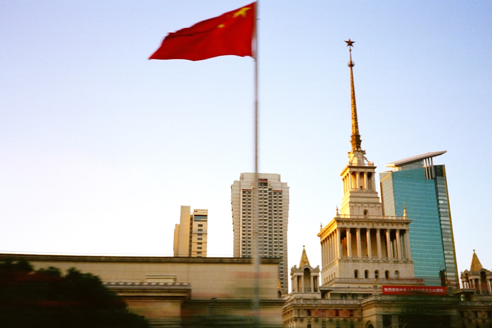 a red flag flying in front of a tall building