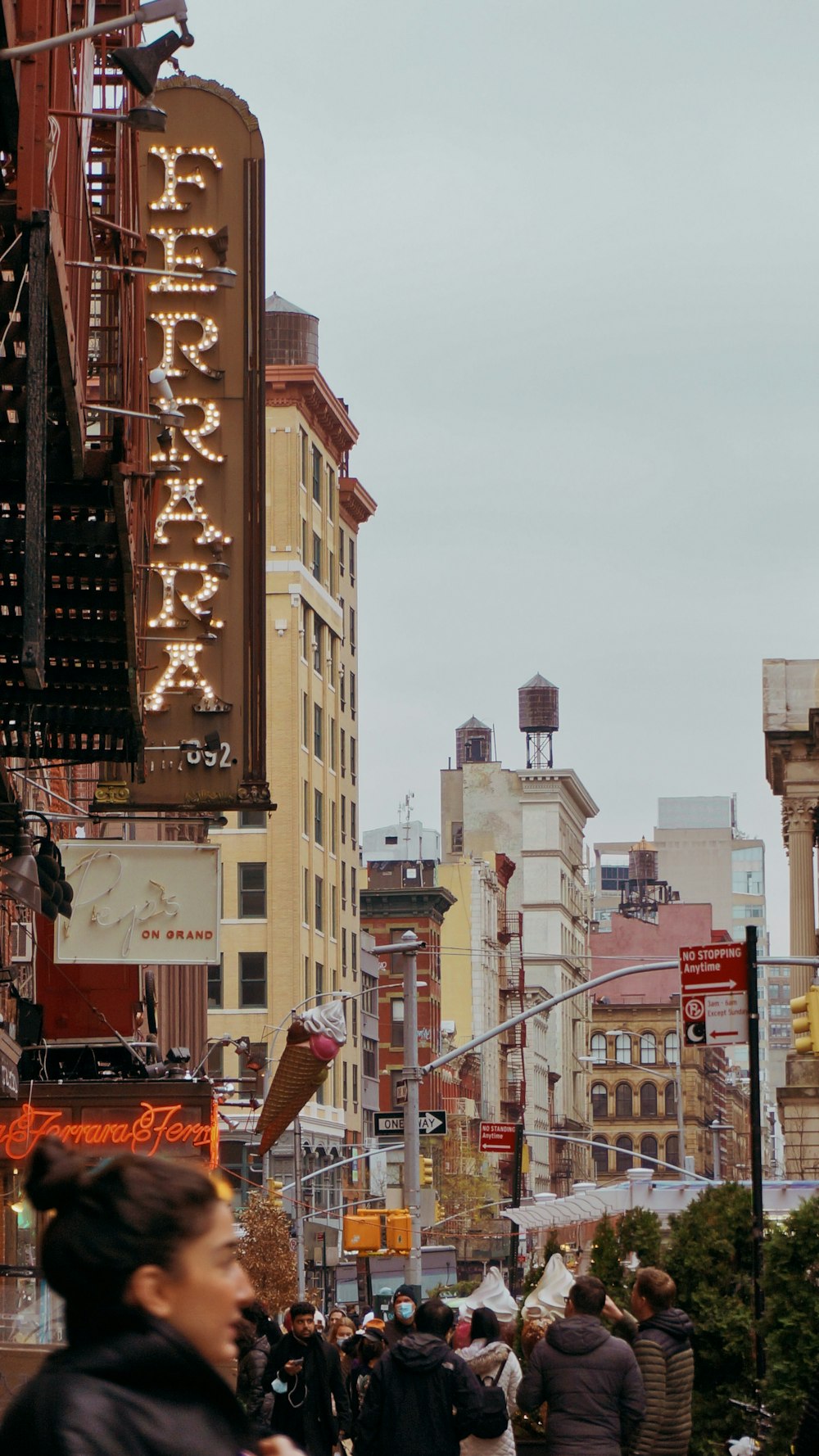 a crowd of people walking down a street next to tall buildings