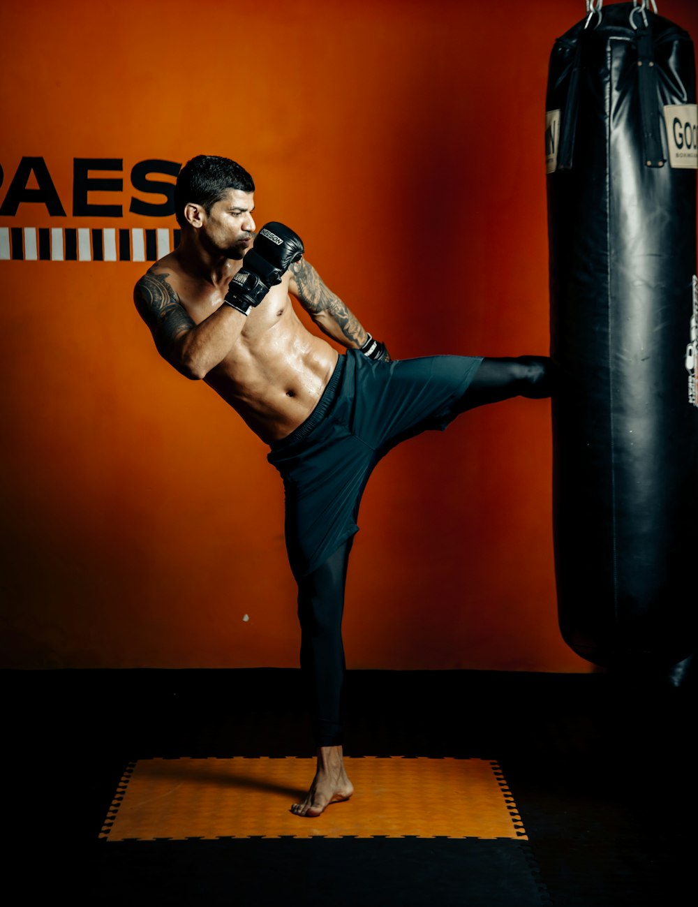 a man standing on a mat in front of a punching bag