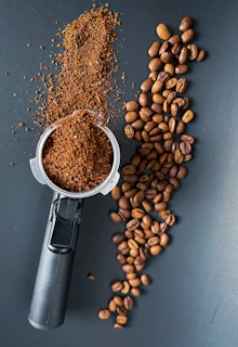 Modern coffee grinder with freshly ground coffee spilling gently onto a dark surface