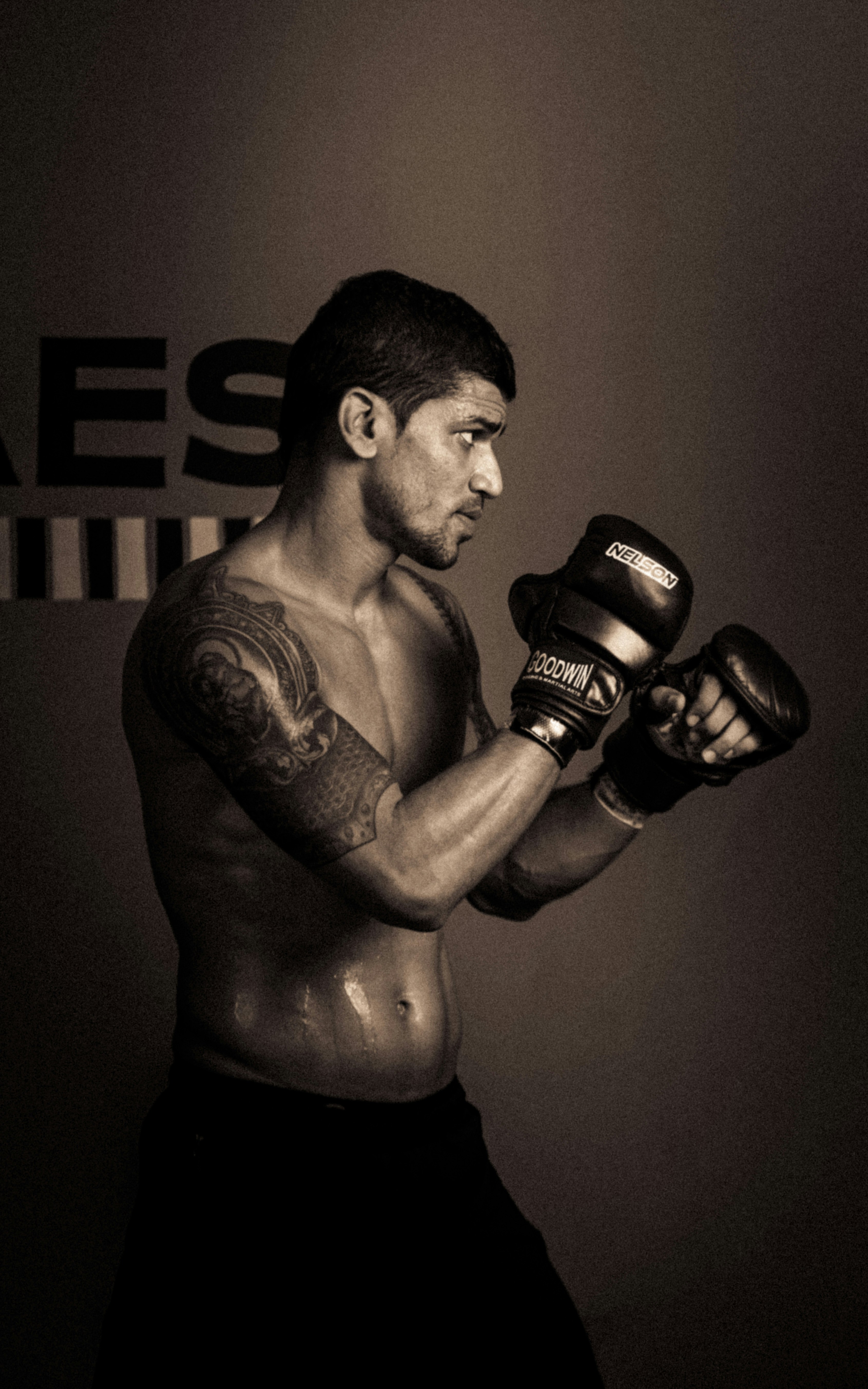 Un hombre con un tatuaje en el brazo sosteniendo un par de guantes de boxeo