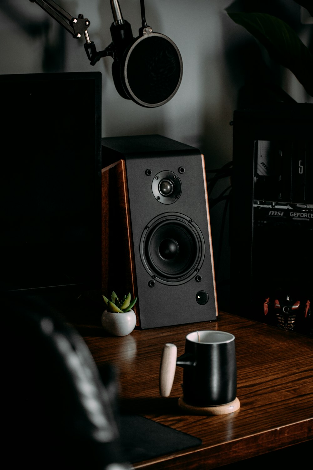 a desk with a speaker and a cup on it