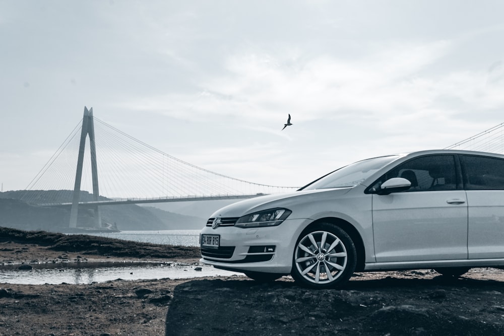 a white car is parked on a rock by the water