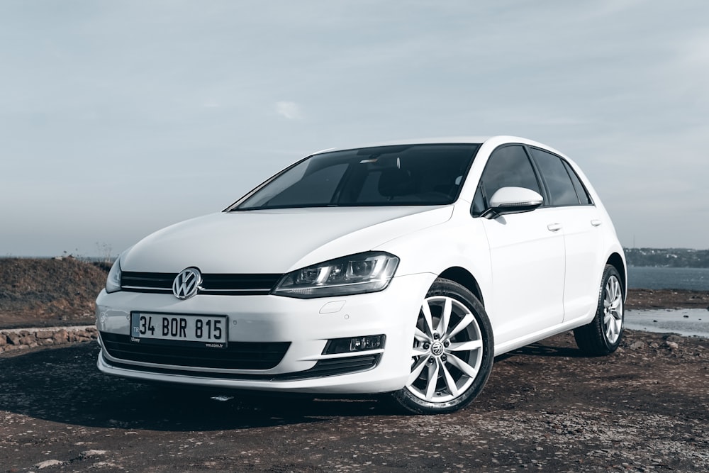 a white car parked on a rocky beach