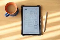 a tablet computer sitting on top of a wooden table next to a cup of coffee