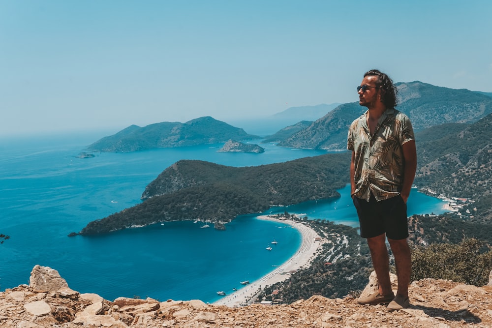 a man standing on top of a mountain next to a body of water