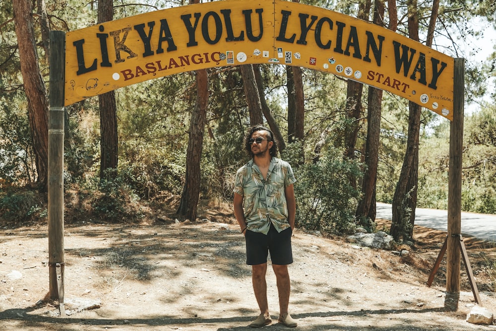 a man standing under a yellow sign in the woods