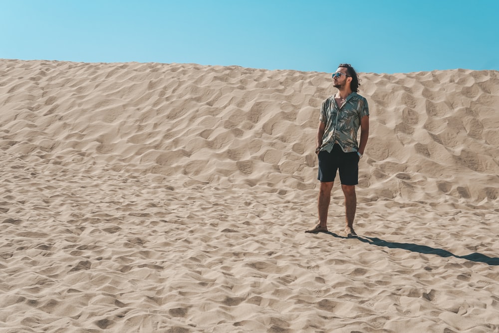 Un homme debout au sommet d’une plage de sable