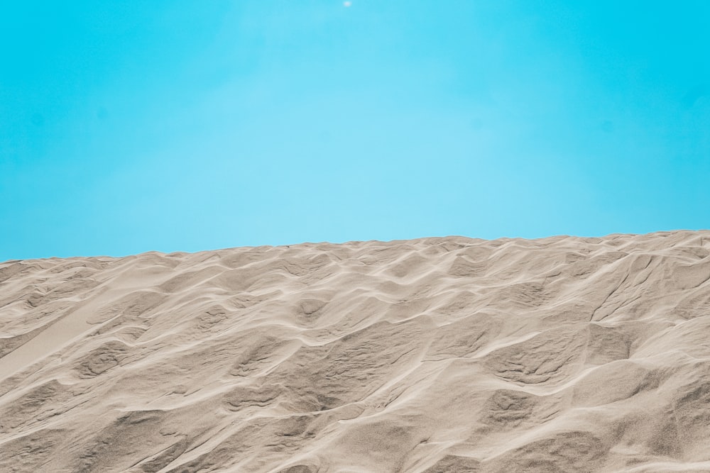 une personne debout au sommet d’une colline de sable