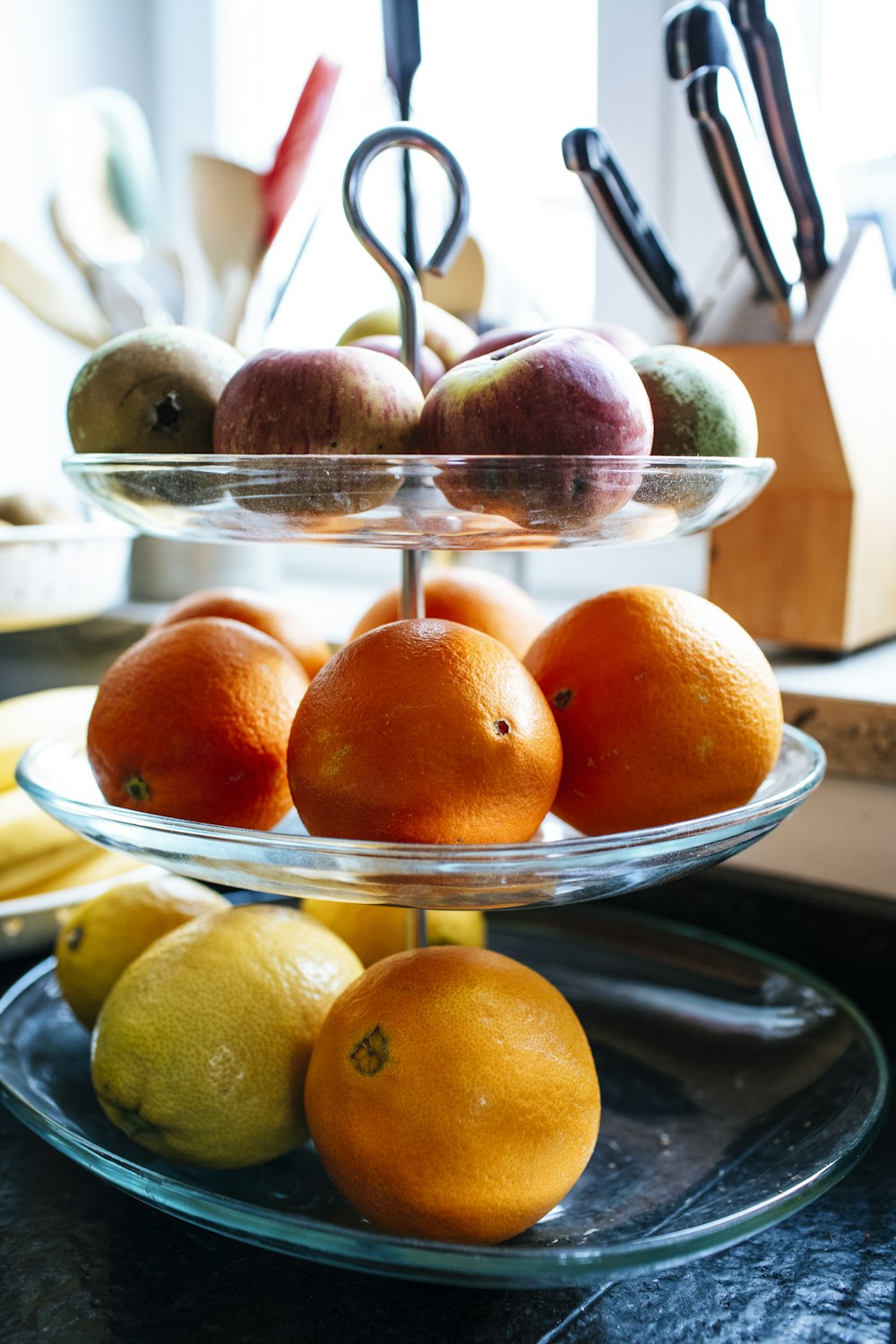 a three tiered glass plate filled with oranges and lemons