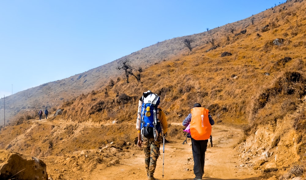 a couple of people walking down a dirt road