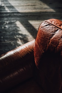 a brown leather couch sitting on top of a wooden floor