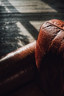 a brown leather couch sitting on top of a wooden floor