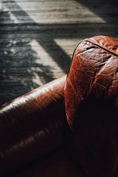 a brown leather couch sitting on top of a wooden floor