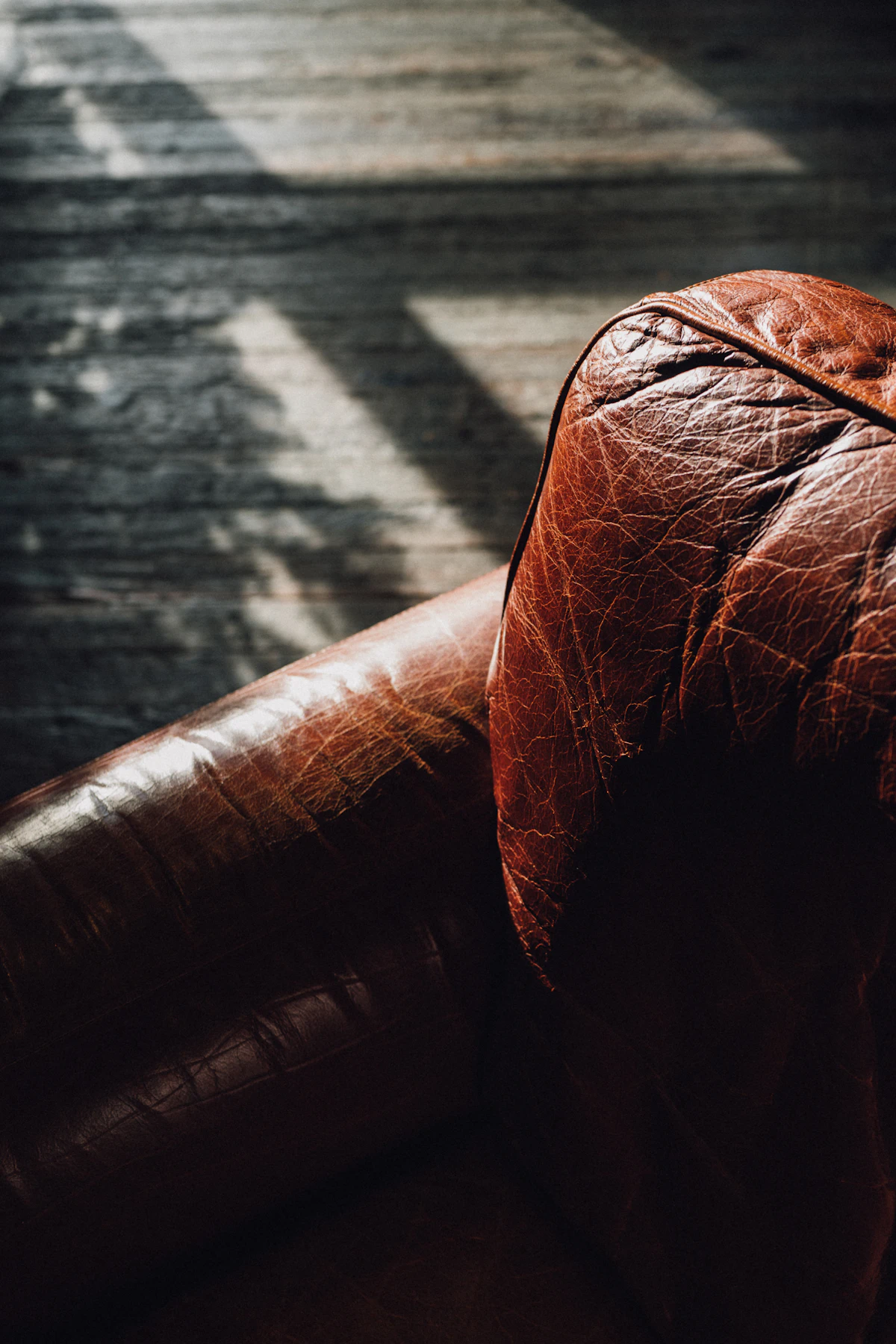 Worn leather chair facing a darkened brick wall.