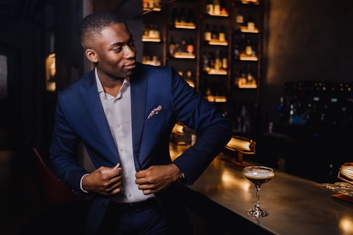 A stylish gentleman in a tailored suit enjoying a cocktail at a luxurious venue.