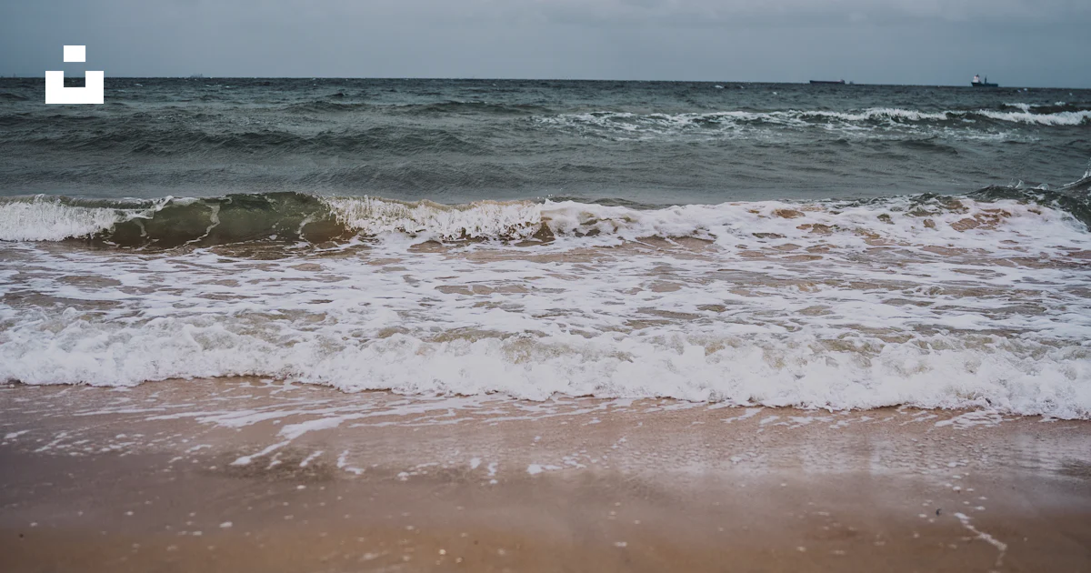 Une plage de sable avec des vagues qui arrivent sur le rivage photo ...