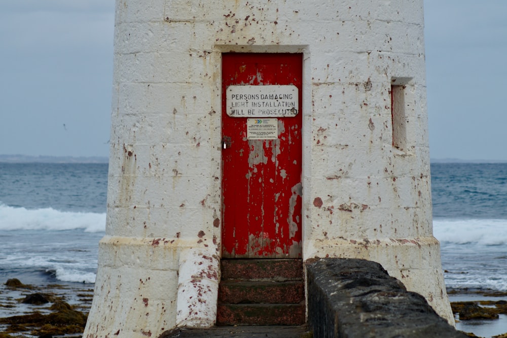 a lighthouse with a red door and a sign on it