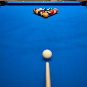 a pool table with a pool ball and cues