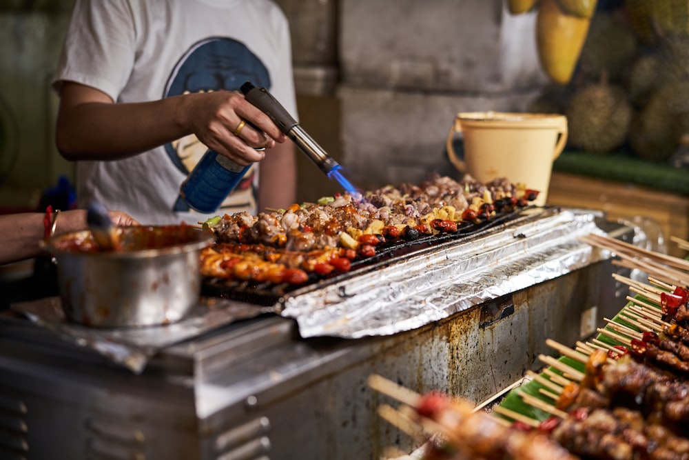 a person cooking food on a grill with tongs