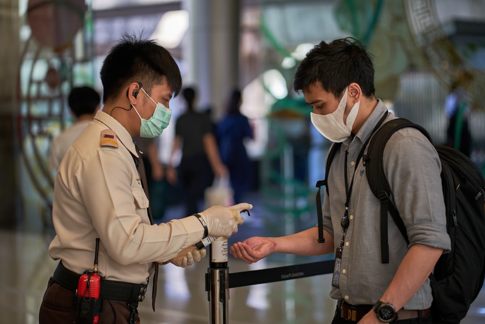 two men wearing face masks at an airport