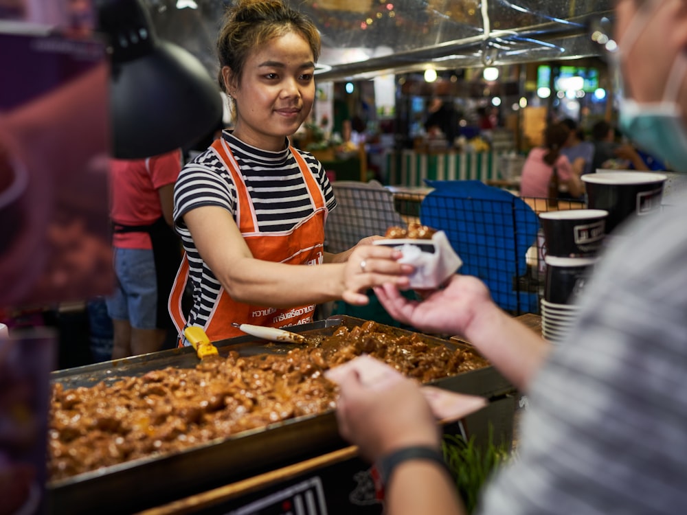 a woman in an apron is serving food to another woman