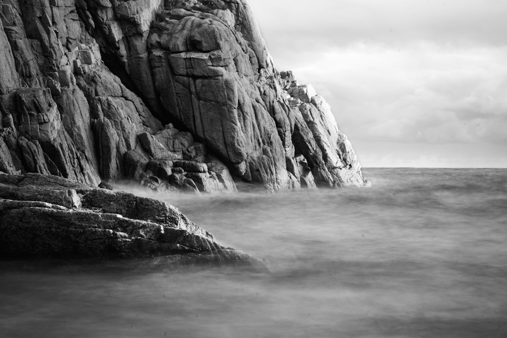 a black and white photo of a rock outcropping in the ocean