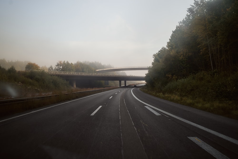 a foggy road with a bridge in the distance